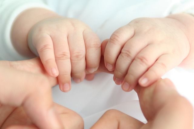 Deux mains de bébé qui serrent deux doigts d'adulte
